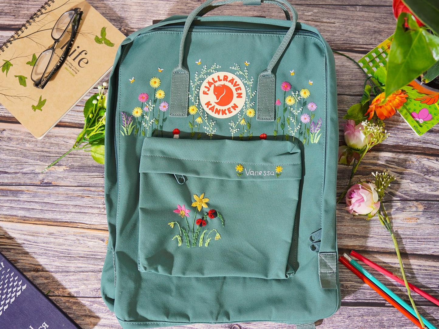 Fjallraven kanken backpack embroidered with ladybugs and colorful flowers, Ladybug embroidery design on Fjallraven Kanken backpack