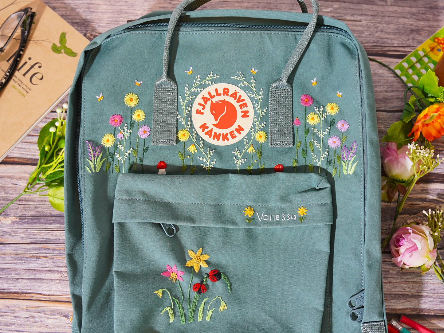 Fjallraven kanken backpack embroidered with ladybugs and colorful flowers, Ladybug embroidery design on Fjallraven Kanken backpack